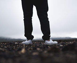 A person's legs standing in the dirt on a foggy/cloudy day