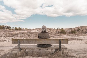 Older woman in Utah sitting on a bench in the desert, waiting for addiction help