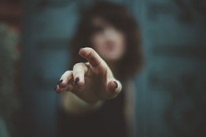 Blurry image of a woman with painted nails pointing at the camera