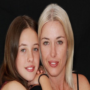 Mother and daughter posing together against black background