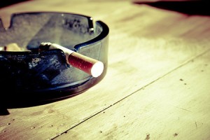 Cigarette in an ashtray on a wooden table