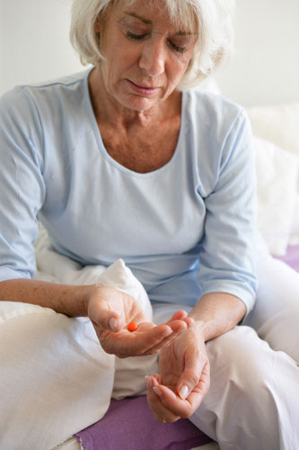 Older woman contemplating taking an antidepressant pill 