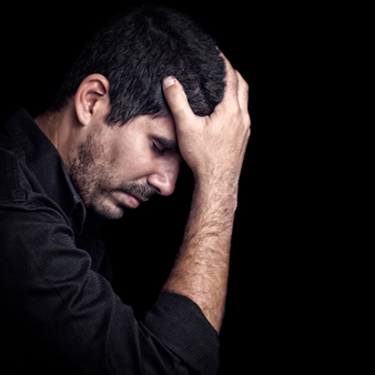Man holding head with one hand in emotional pain against black background