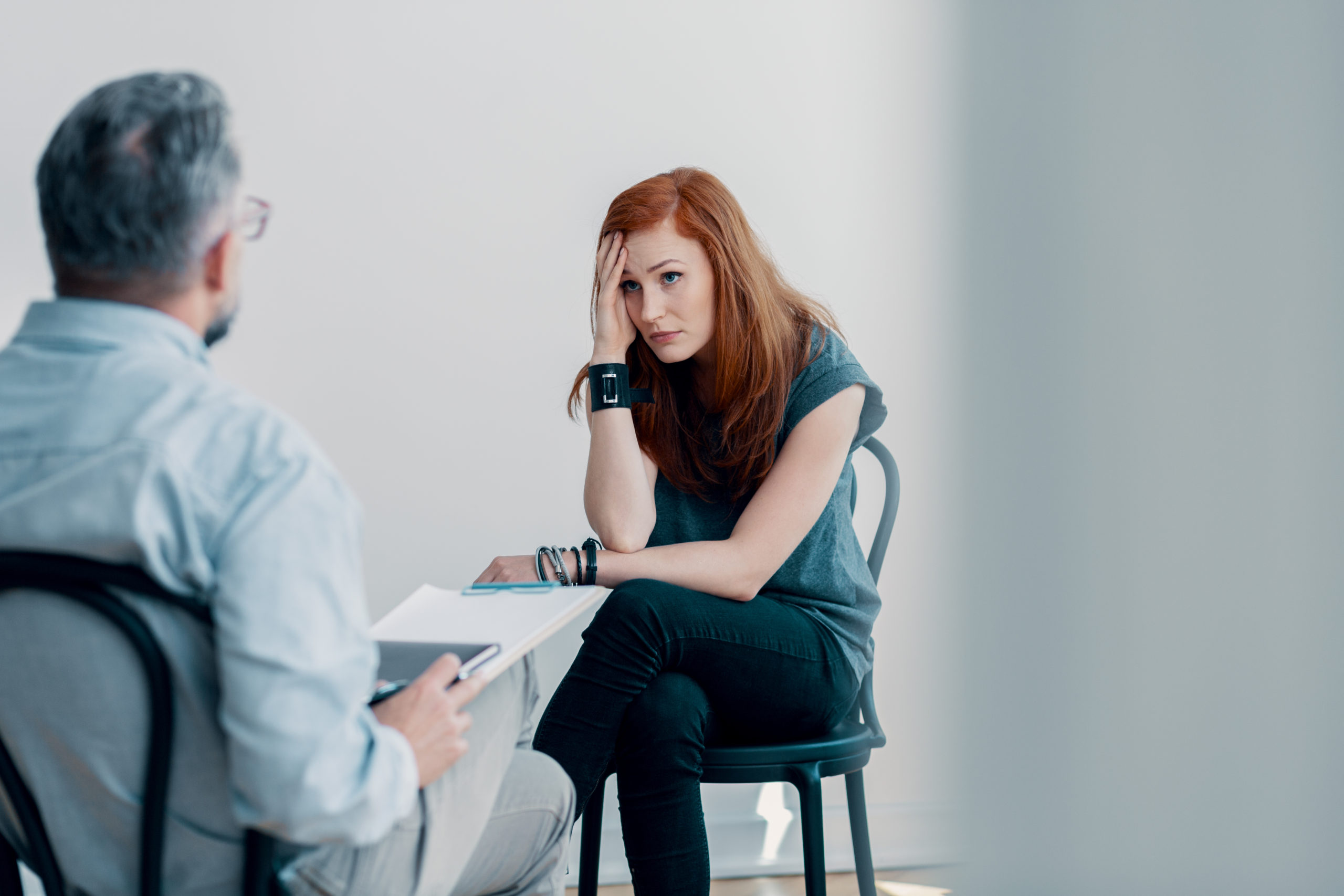 Young woman looking distressed and talking to a therapist.