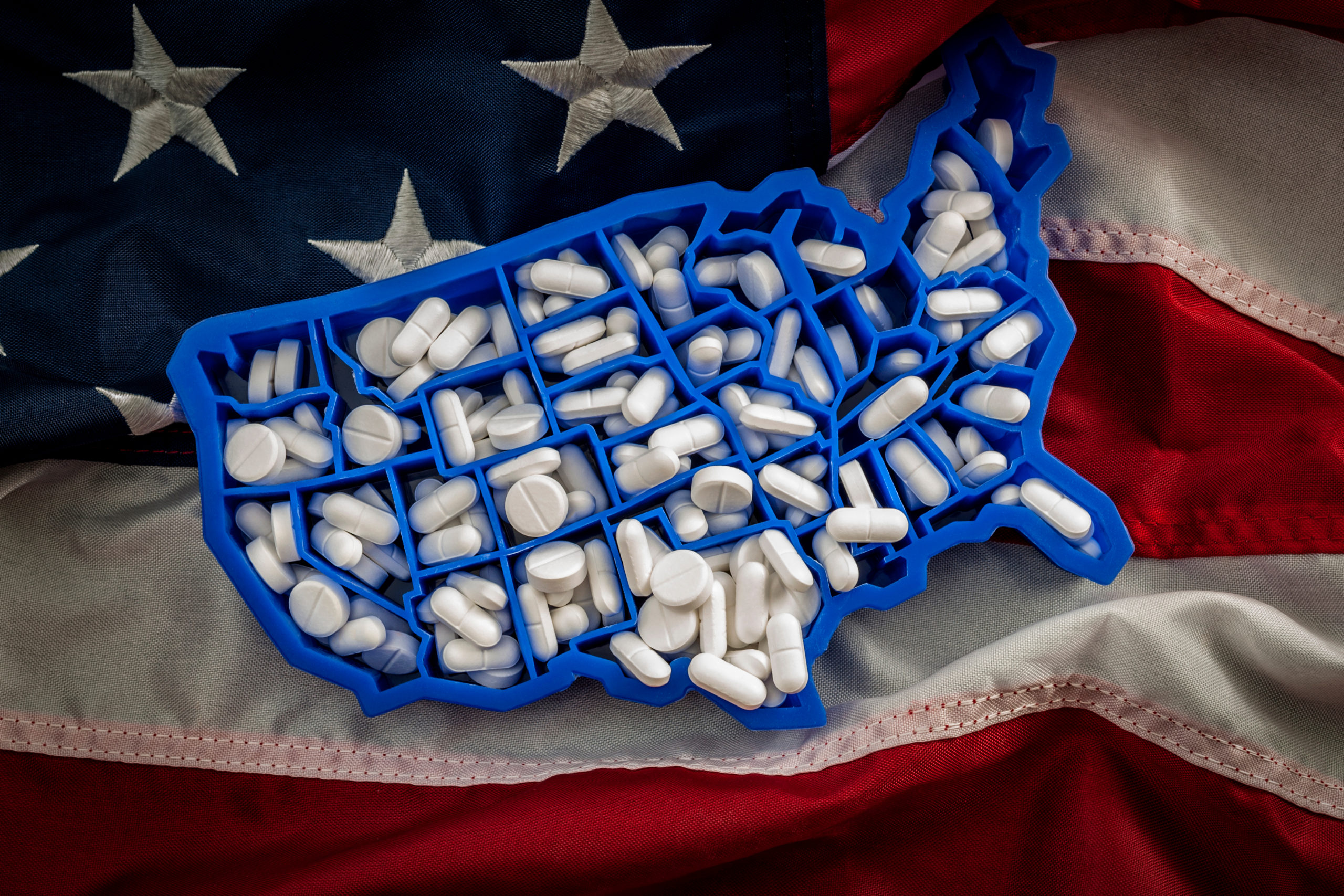Mixture of pills in a USA shaped container laying on a US flag